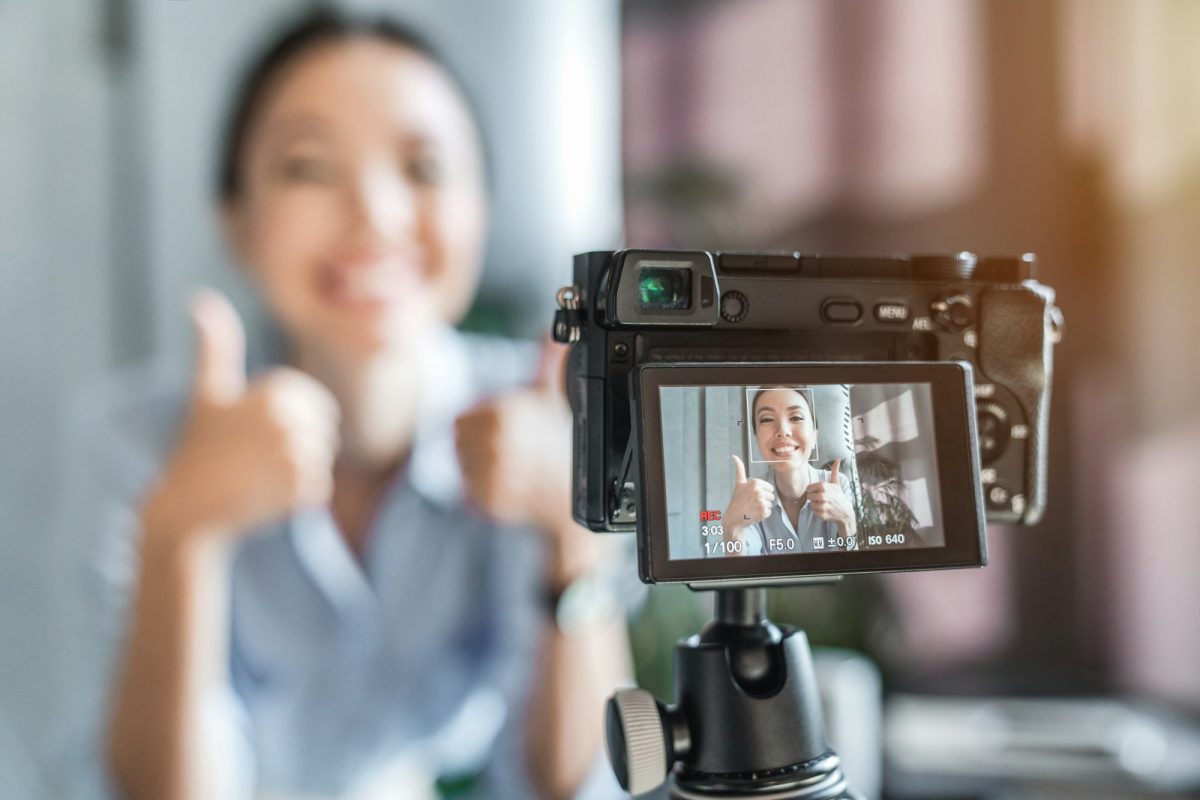 Close up photo of digital camera with young blogger online broadcasting in social media